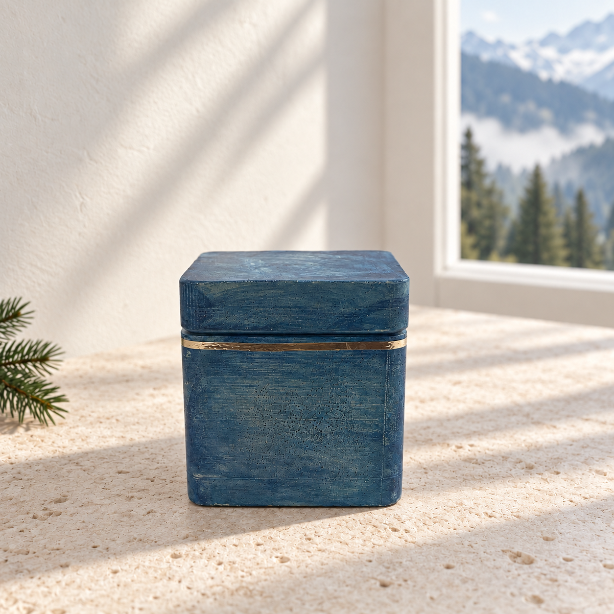 • A closed handcrafted square concrete candle jar in a texturized blue finish with its matching lid on, accented by a hand-applied silver reflective trim band around the rim.