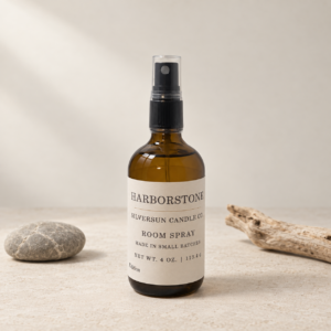 Front view of Harborstone premium ambient room spray bottle by Silversun Candle Co styled on a textured stone surface with driftwood.